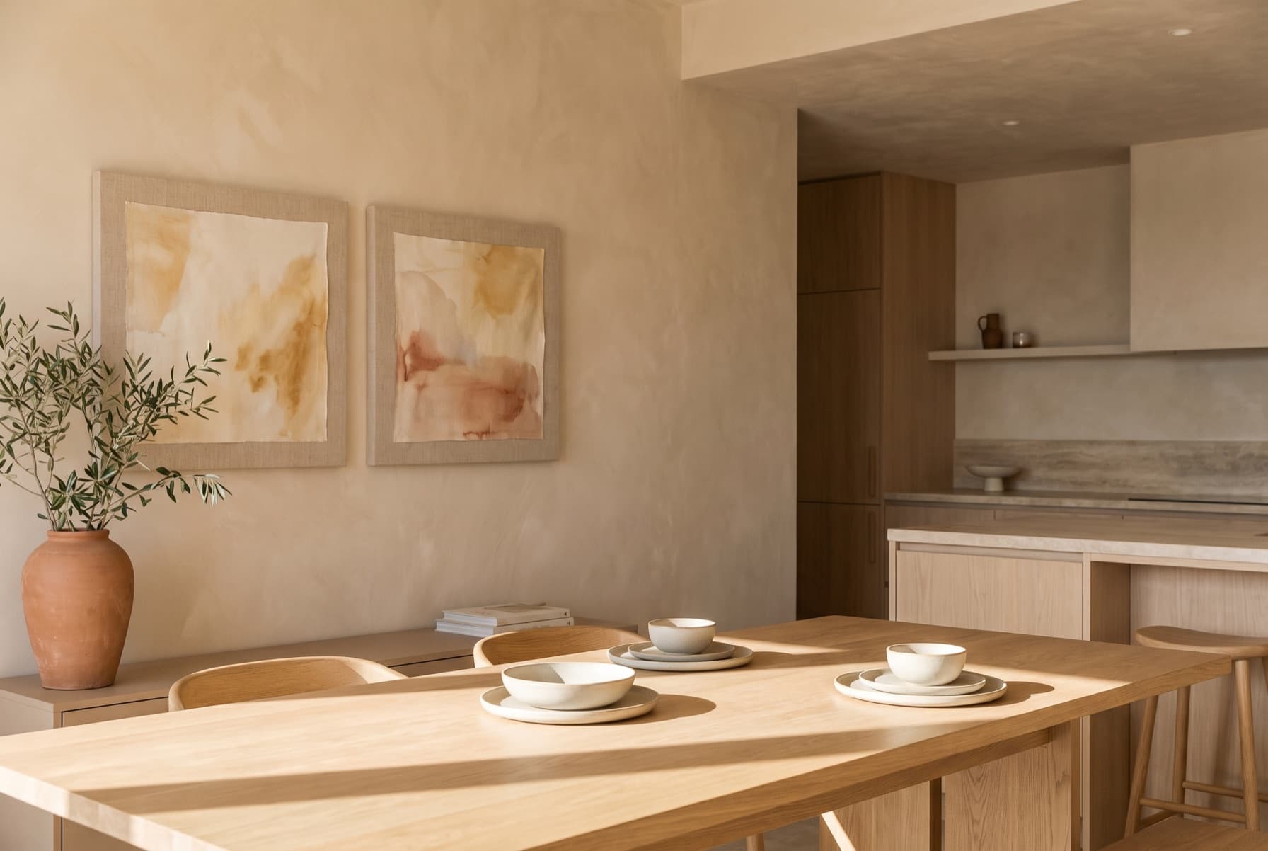 Cocina-comedor con dos acuarelas enmarcadas en lino sobre el aparador, junto a un jarrón de terracota.