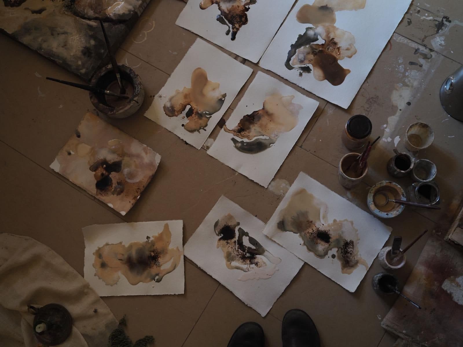 Estudios sobre papel de Carla Kasseroler repartidos por el suelo del taller, junto a pinceles y pigmentos.
