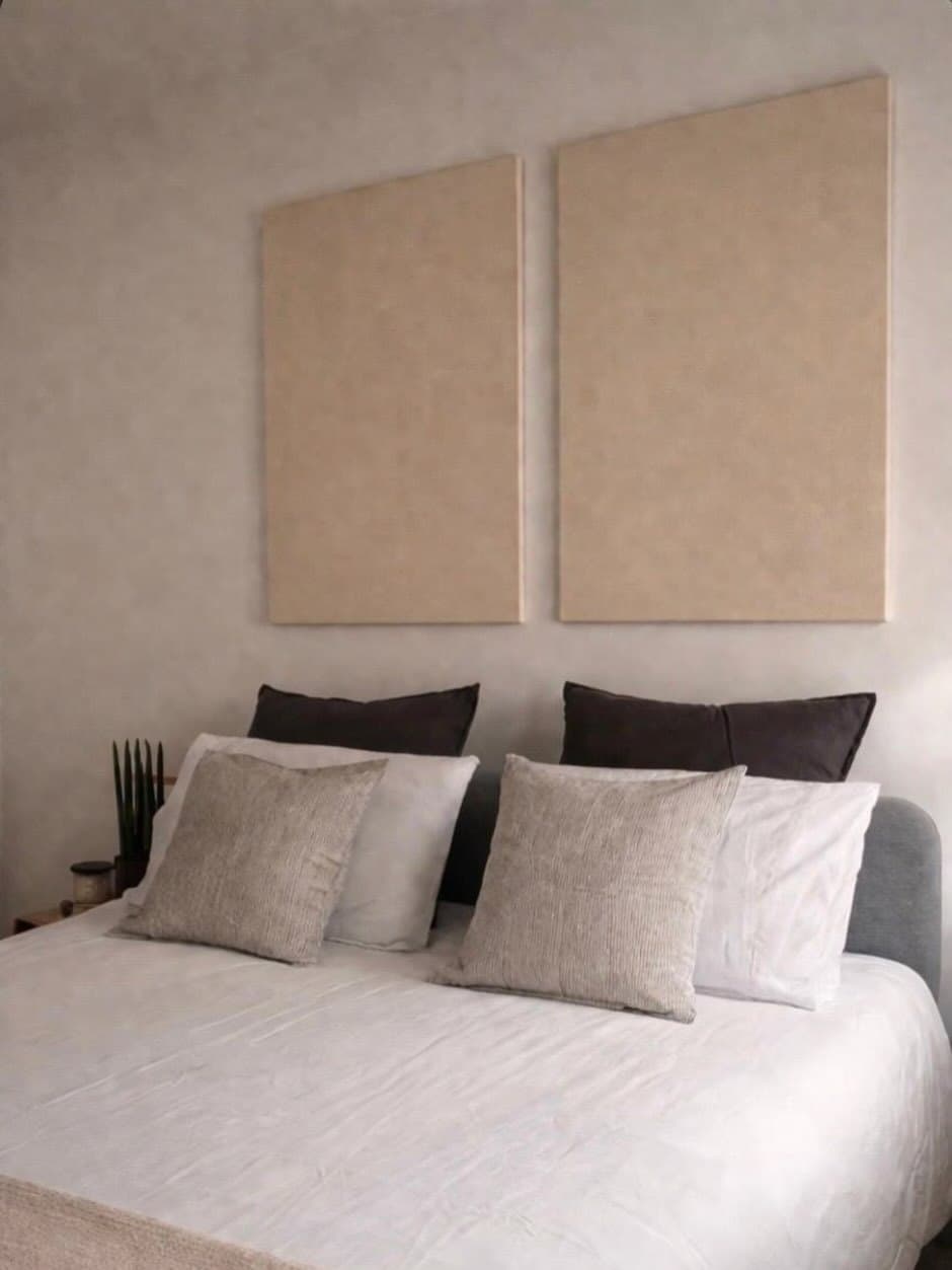 Dos paneles beige de gran formato sobre la cama, sin marco visible.