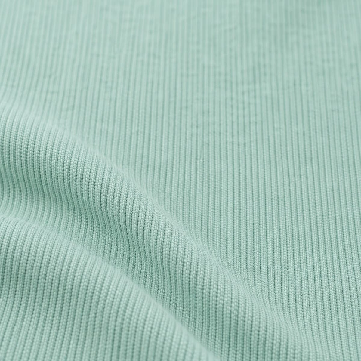Macro de tela de algodón en verde pastel, menta suave con canalé vertical muy fino, con un pliegue suave y luz difusa.